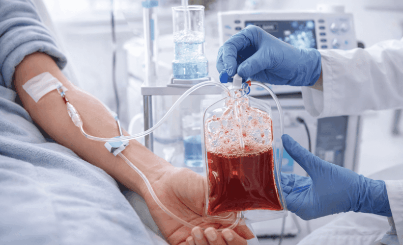 Practitioner holding ozonated blood IV bag connected to patient's arm during blood ozone therapy session
