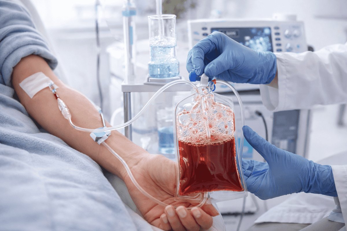 Practitioner holding ozonated blood IV bag connected to patient's arm during blood ozone therapy session