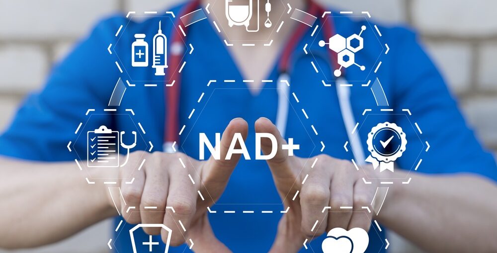 Healthcare provider in blue scrubs displaying a digital NAD+ graphic representing NAD+ IV therapy benefits and applications