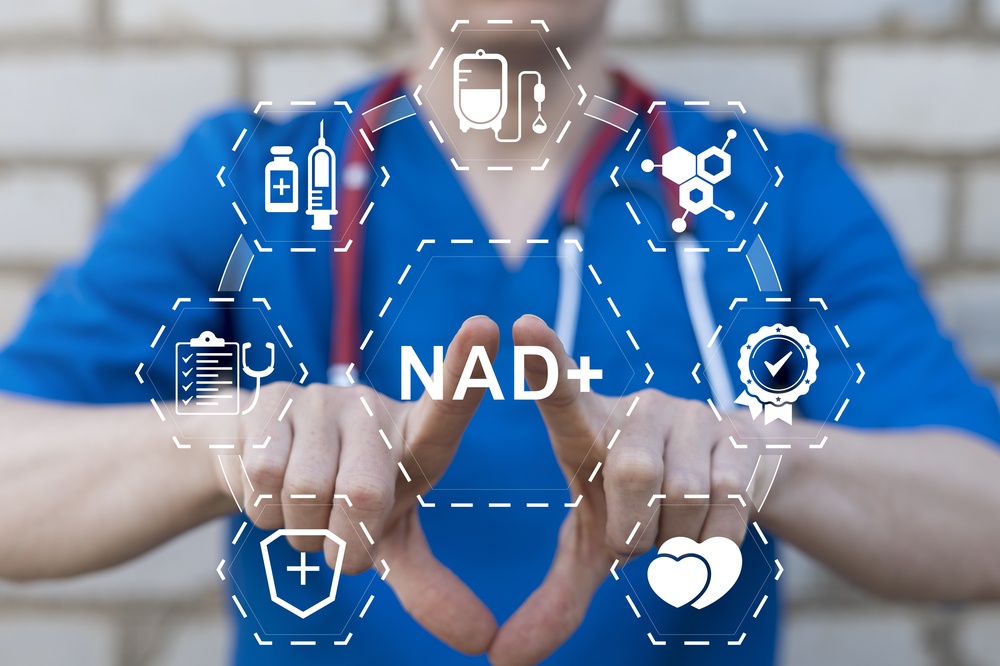 Healthcare provider in blue scrubs displaying a digital NAD+ graphic representing NAD+ IV therapy benefits and applications