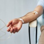 Male patient sitting with an IV line in his forearm during an IV therapy for immune support session in a clinical wellness setting