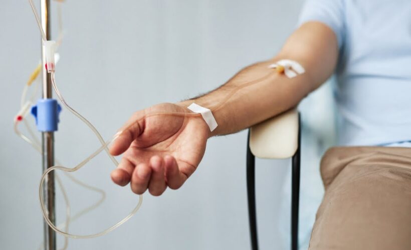 Male patient sitting with an IV line in his forearm during an IV therapy for immune support session in a clinical wellness setting